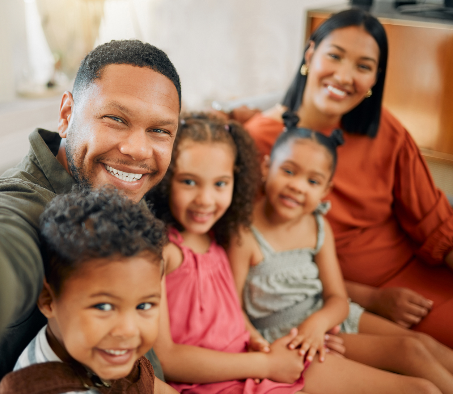 Smiling family seated together on a couch in a warm indoor setting