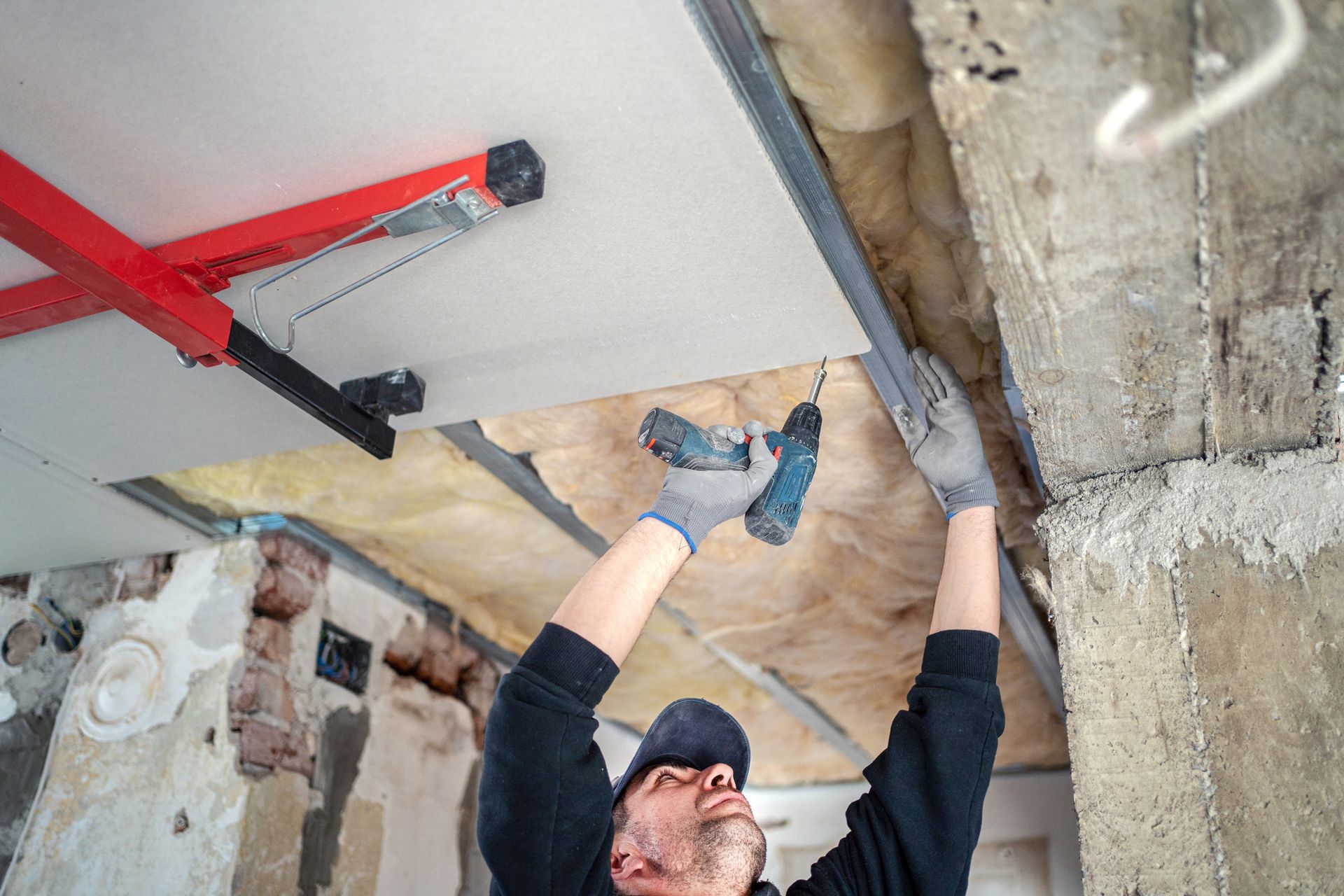 A man is working on a ceiling with a drill.