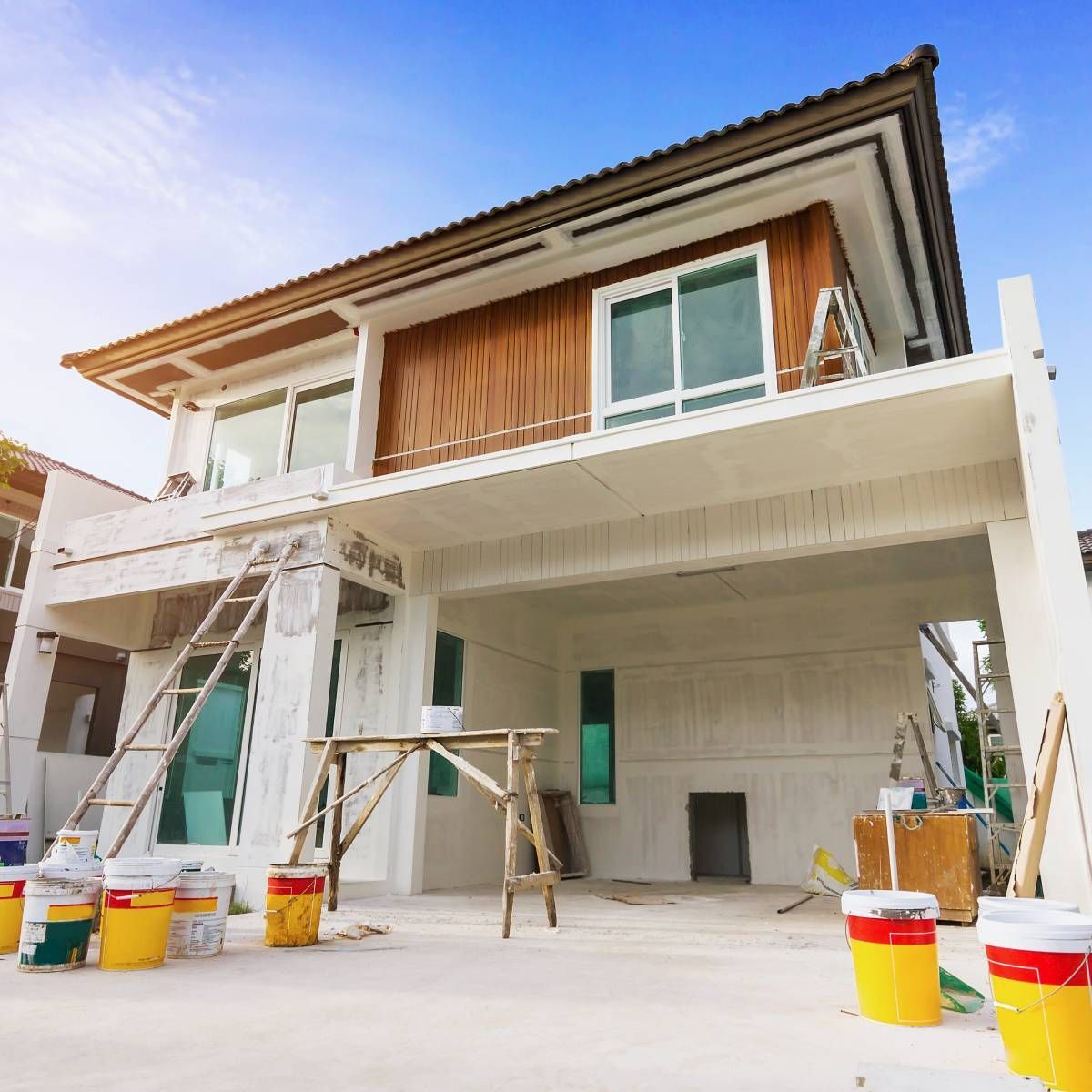 A house under construction with buckets of paint in front of it.