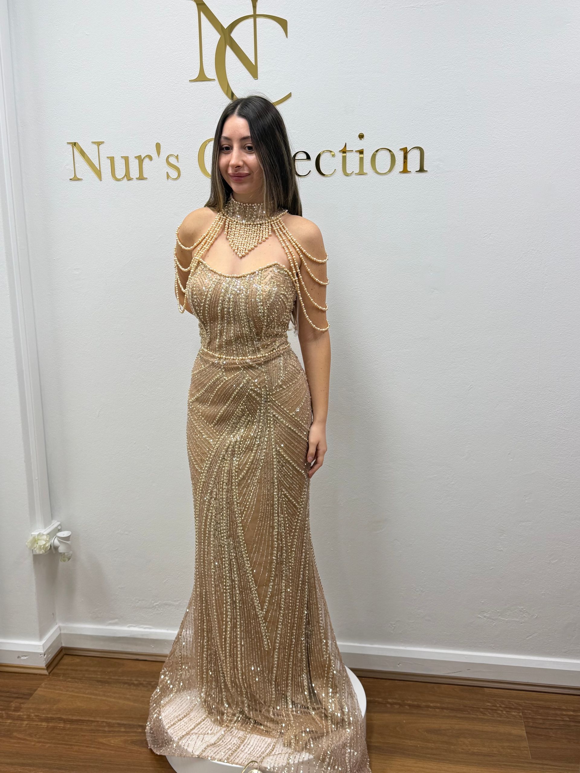 Woman in a Gold Sequin Gown Standing Against a Branded Wall — Nur's Collection In Rockdale, NSW