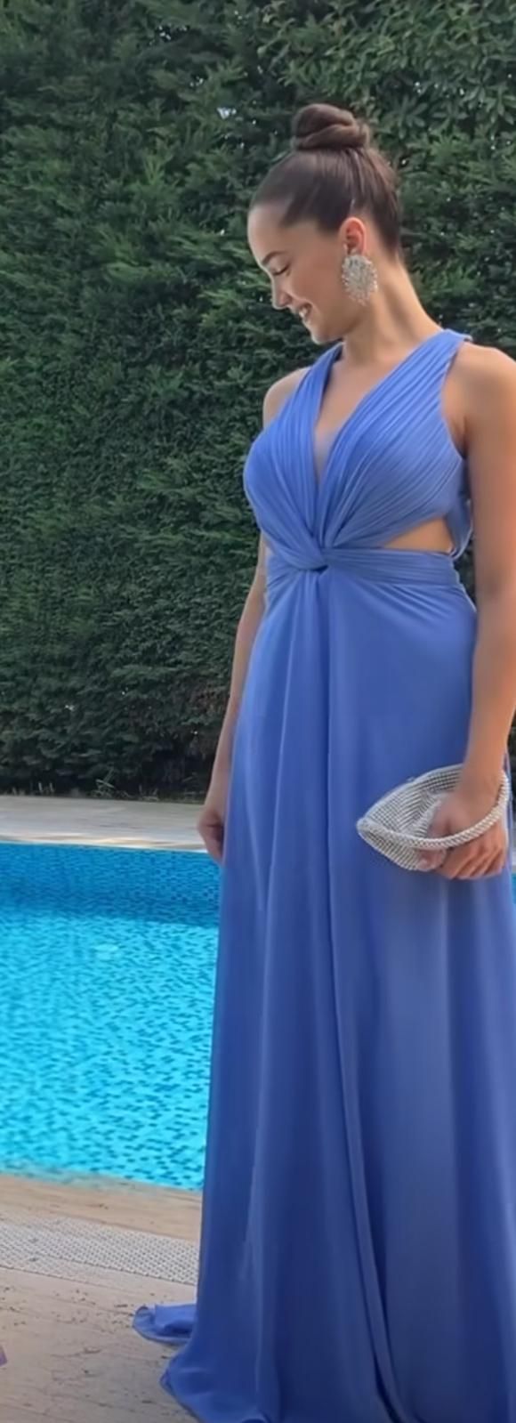 Woman in a Blue Dress Standing by a Pool, Looking Down and Holding a Woven Clutch — Nur's Collection In Rockdale, NSW