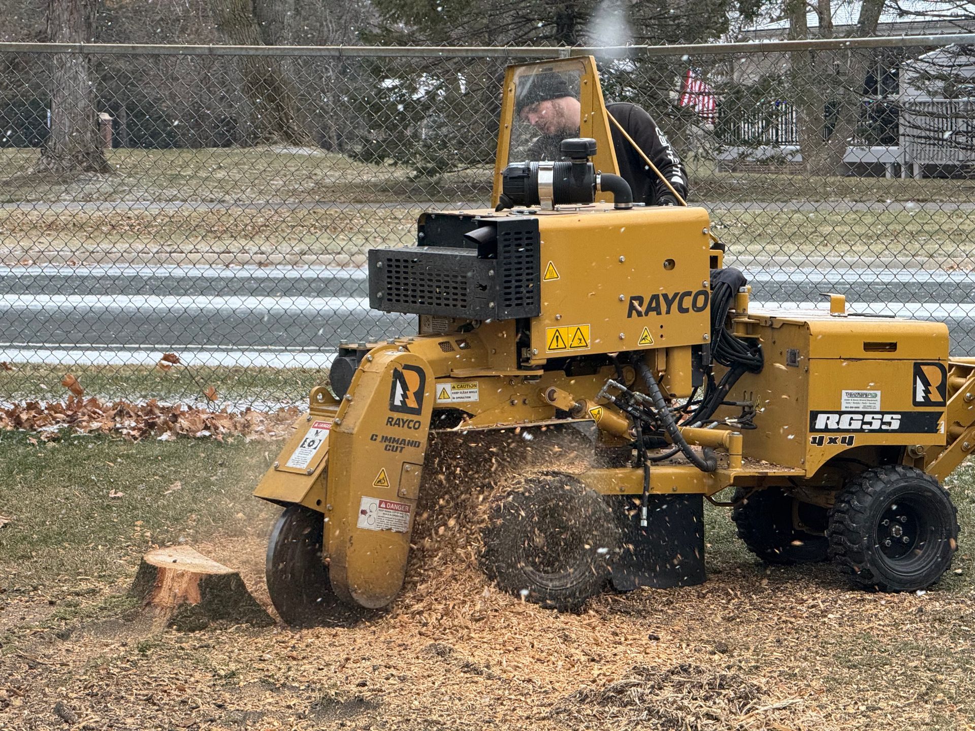 A man is using a stump grinder to remove a tree stump.