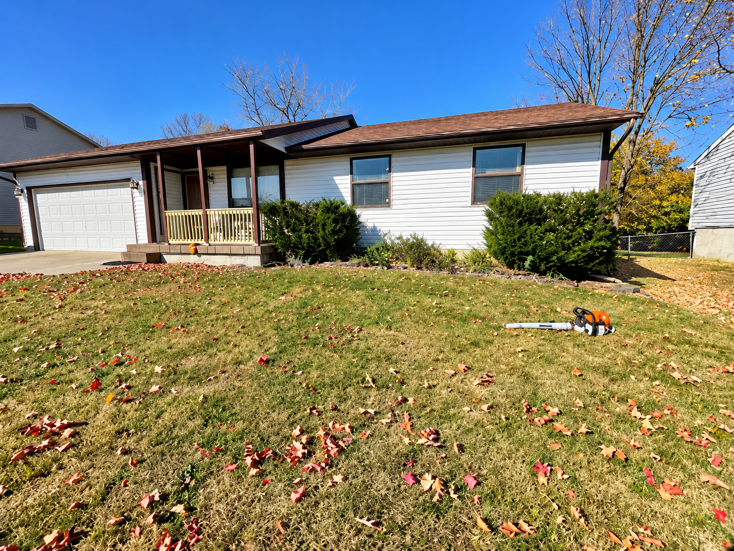 Single-story suburban house with white siding, garage, and a lawn under a clear blue sky. Single-story suburban house with white siding, garage, and a lawn under a clear blue sky.