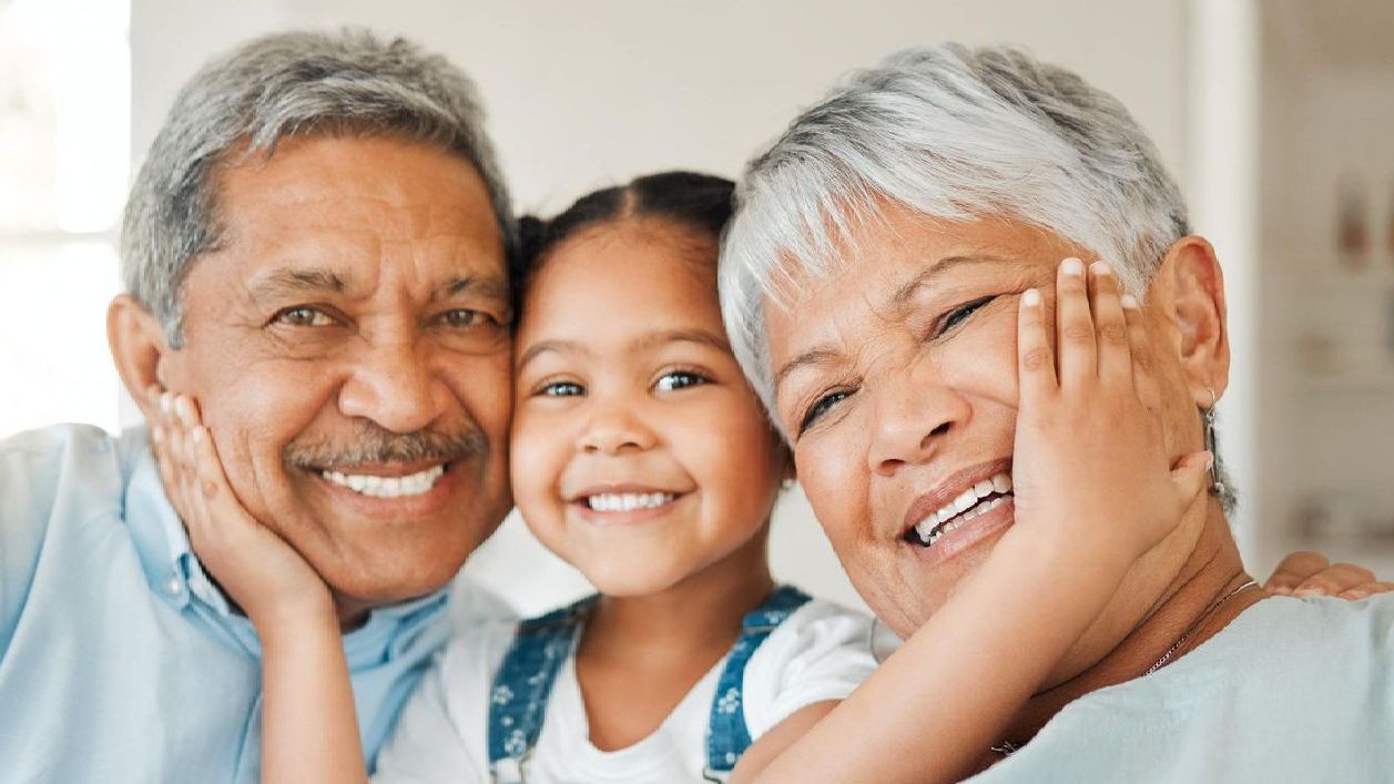 A man and woman are holding a little girl and smiling for the camera.