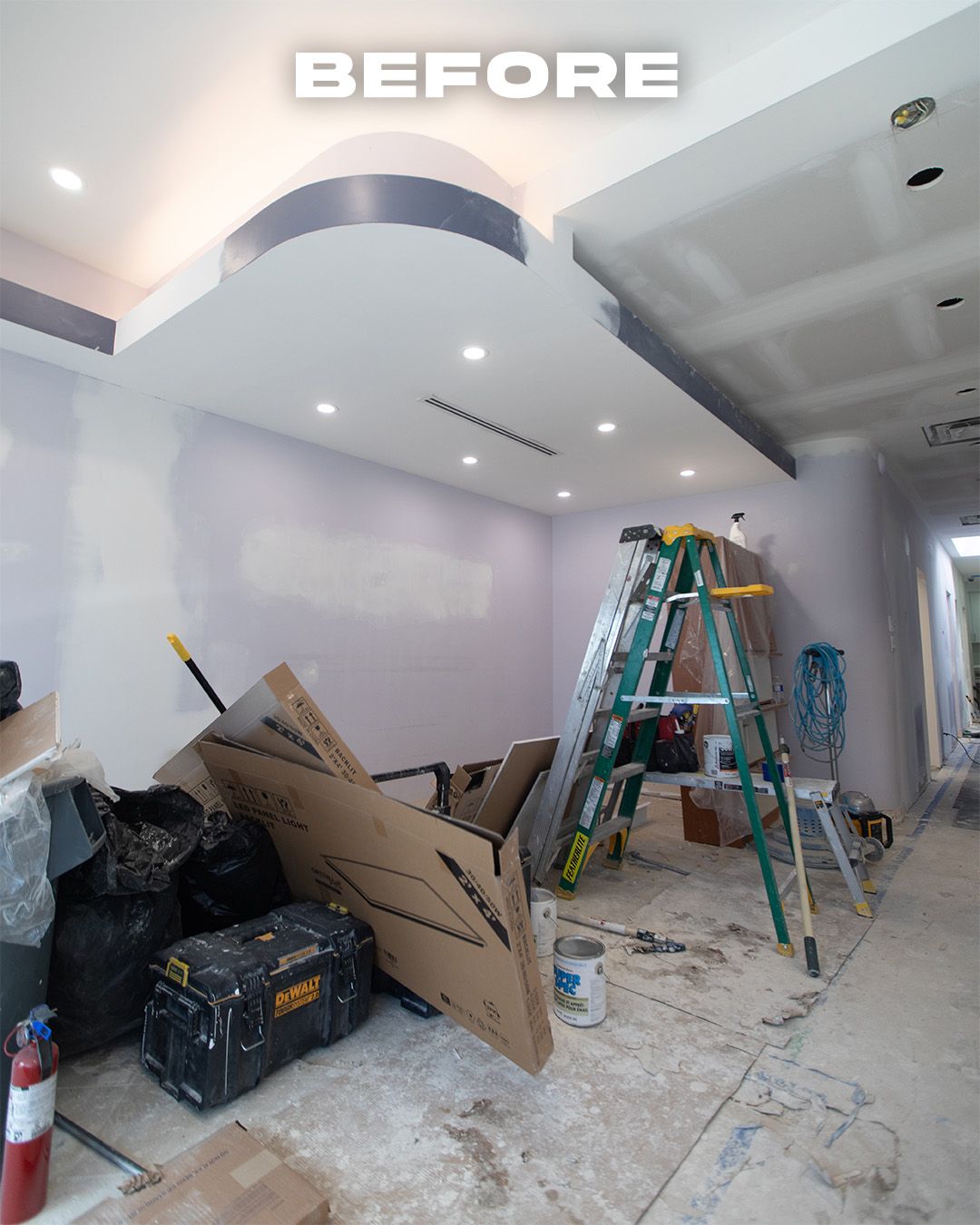 Interior under construction with debris, ladders, and drywall. 