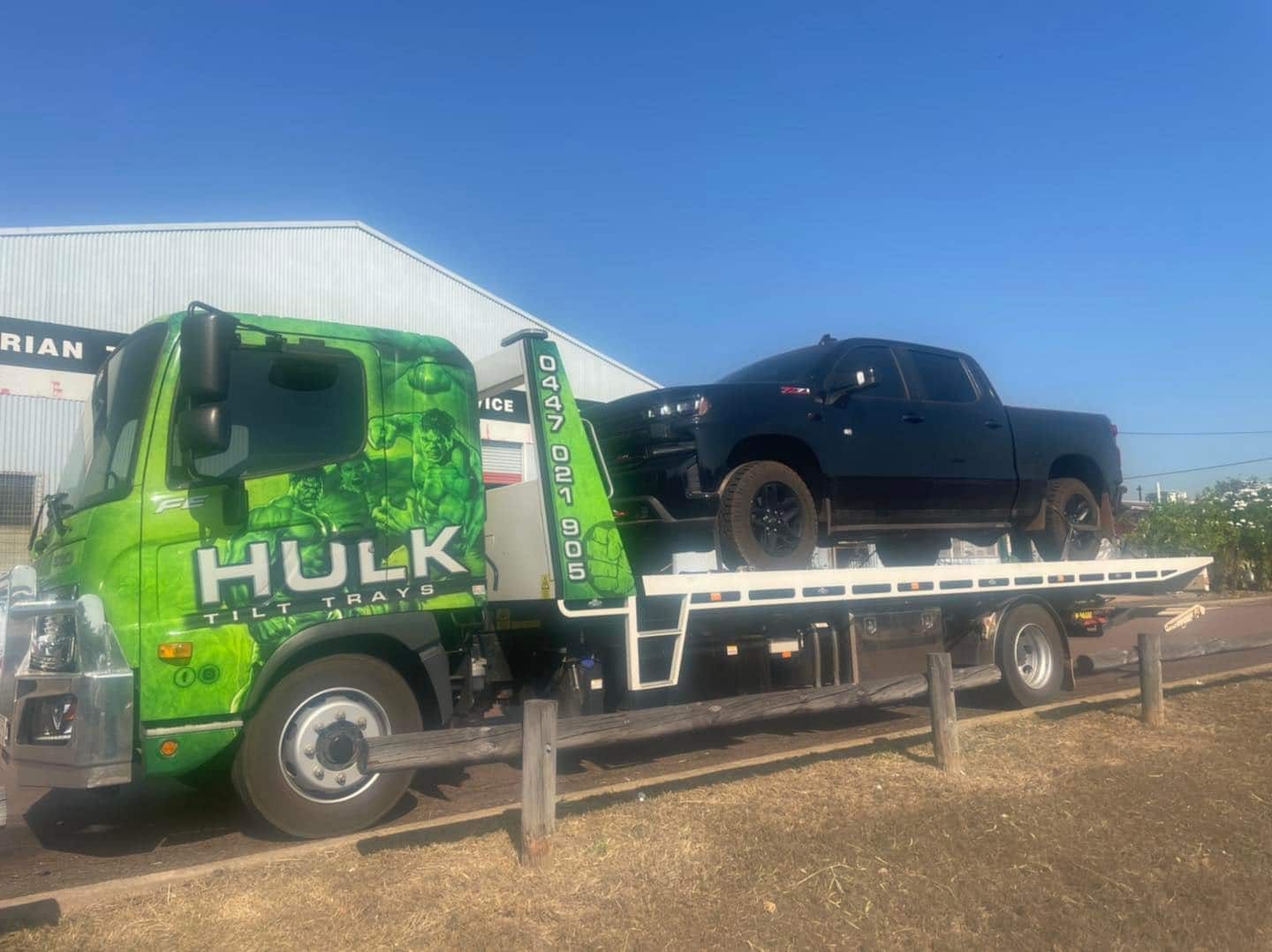 A Green Tow Truck Is Towing a Black Truck — Hulk Tilt Trays In Palmerston, NT