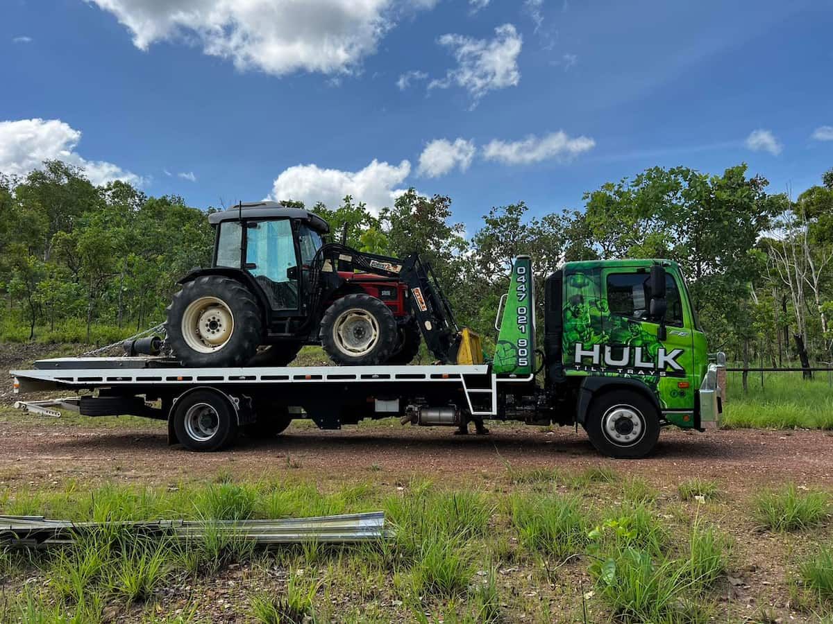 A Tow Truck Is Carrying a Tractor on The Back of It — Hulk Tilt Trays In Palmerston, NT