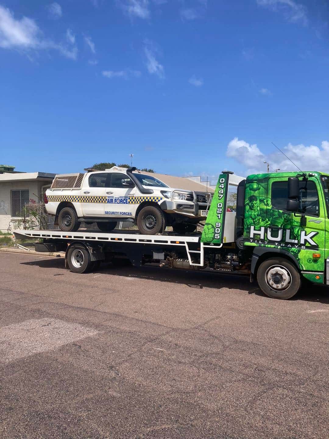 A Green Tow Truck Is Towing a White Truck — Hulk Tilt Trays In Humpty Doo, NT