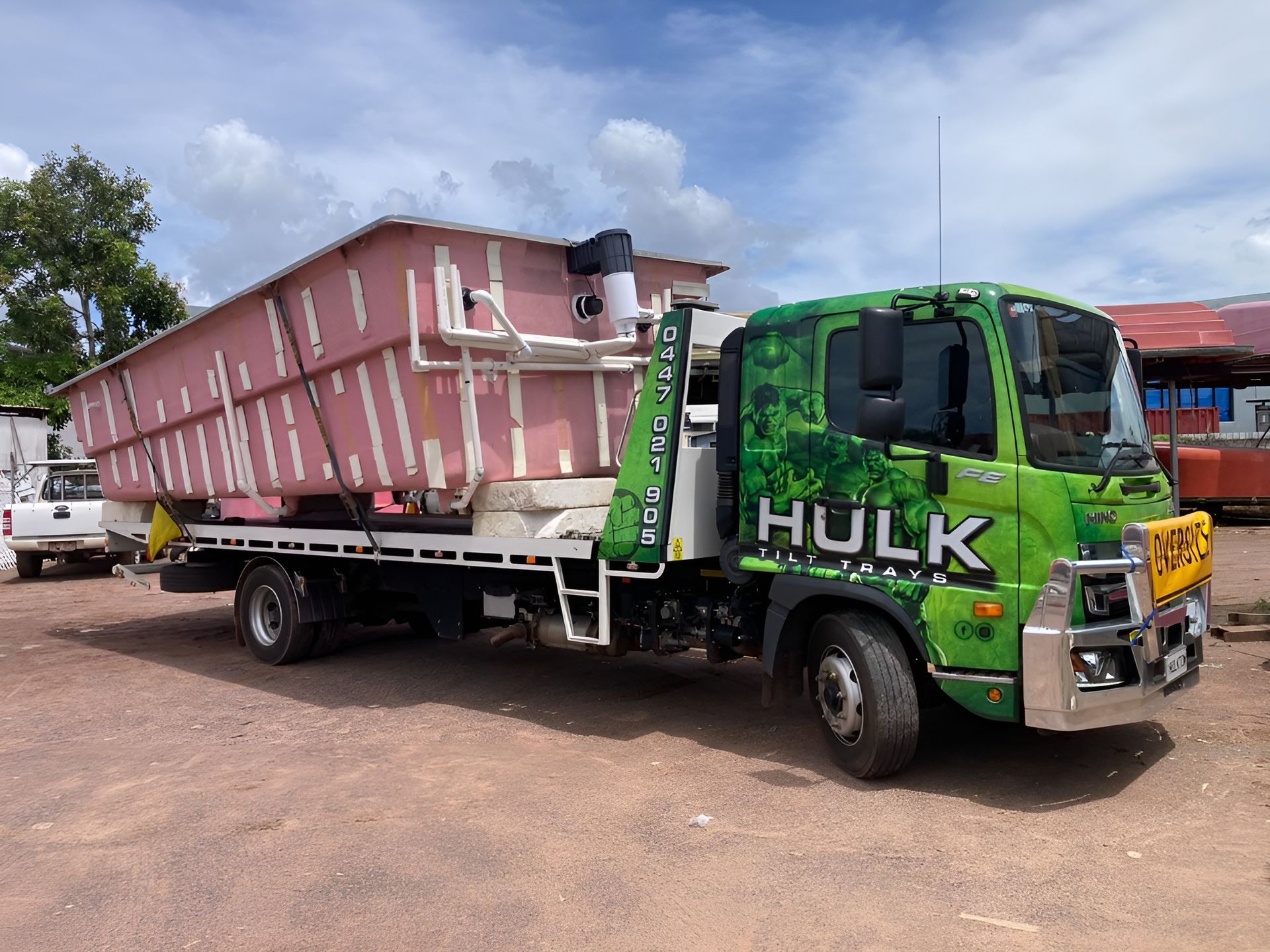 A Green Tow Truck is Carrying a Large Swimming Pool — Hulk Tilt Trays In Humpty Doo, NT