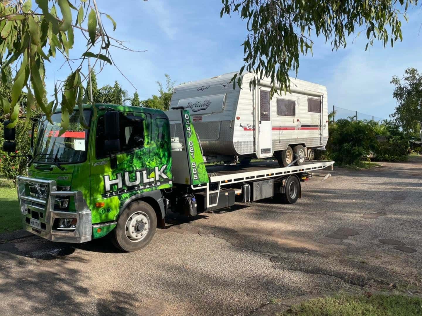 A Green Tow Truck Is Towing a Camper Trailer — Hulk Tilt Trays In Humpty Doo, NT