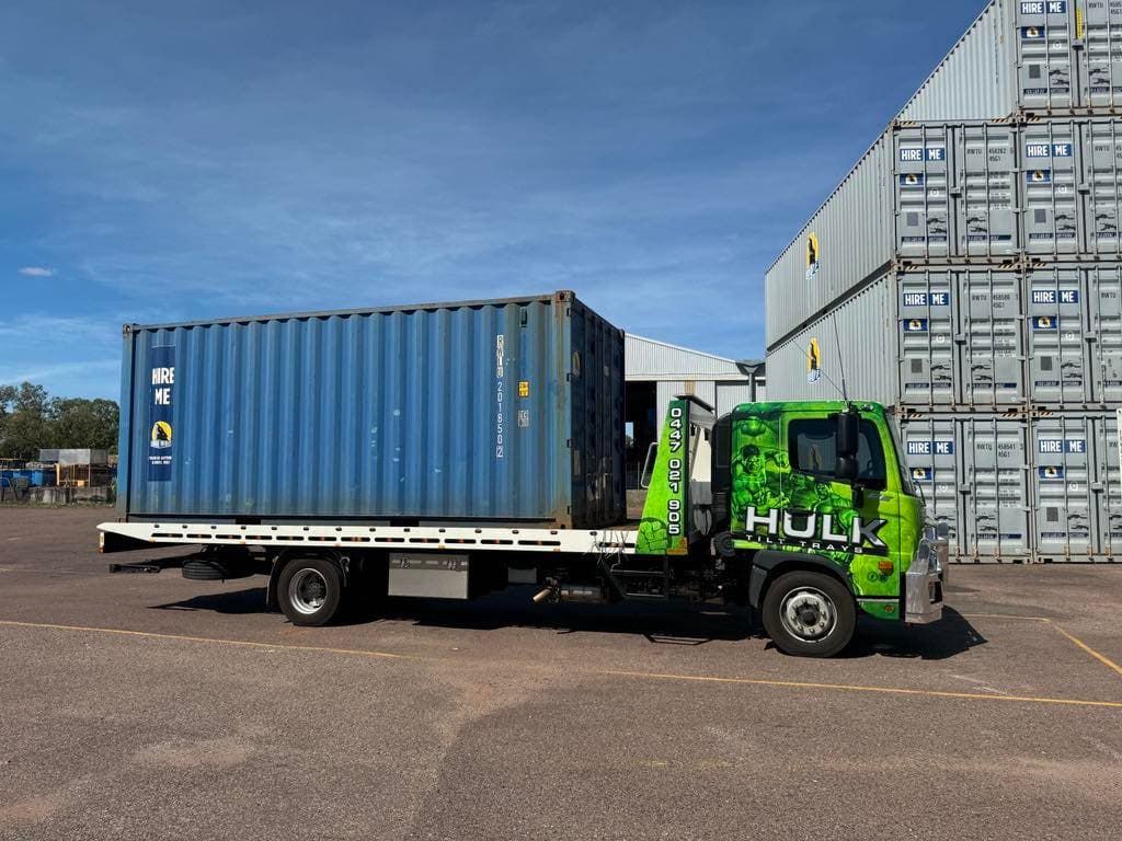 A Tow Truck Is Carrying a Shipping Container in A Parking Lot — Hulk Tilt Trays In Humpty Doo, NT