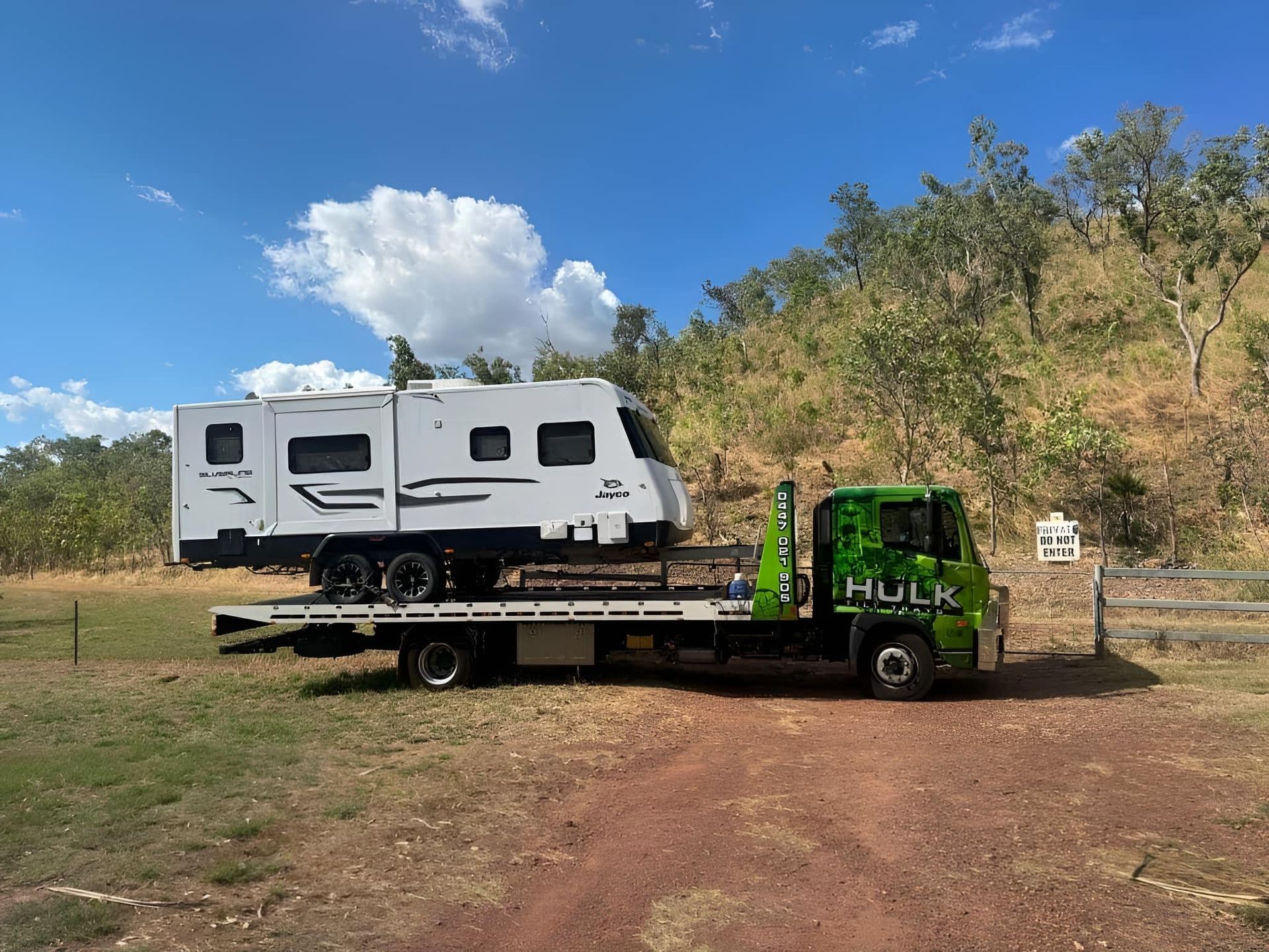 A Green Tow Truck with A White Van on The Back Is Parked on The Side of The Road — Hulk Tilt Trays In Palmerston, NT