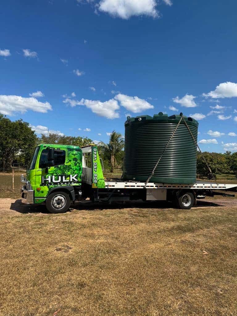 A Green Tow Truck Is Carrying a Large Green Tank on A Flatbed Trailer — Hulk Tilt Trays In Humpty Doo, NT