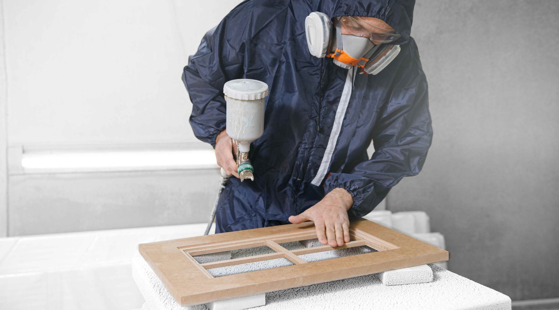A man spraying a cabinet door with paint