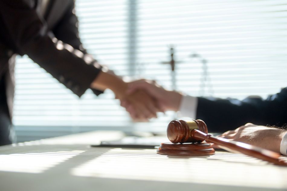 Handshake over a judge’s gavel on a sunlit desk, suggesting a legal agreement Handshake over a judge’s gavel on a sunlit desk, suggesting a legal agreement
