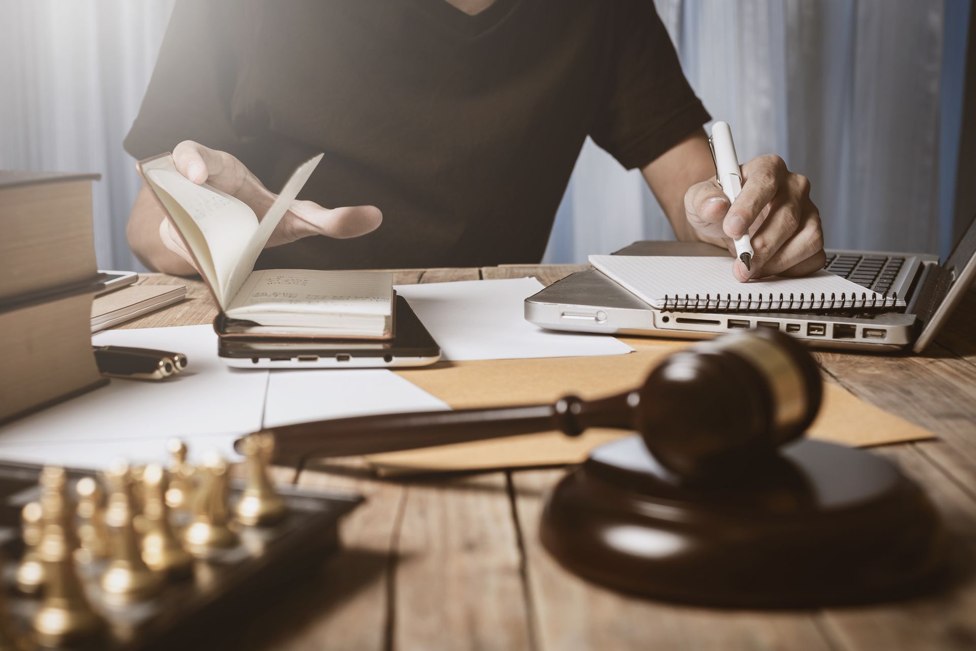 Attorney working at desk with law books, gavel, scales, and documents in a courtroom office setting