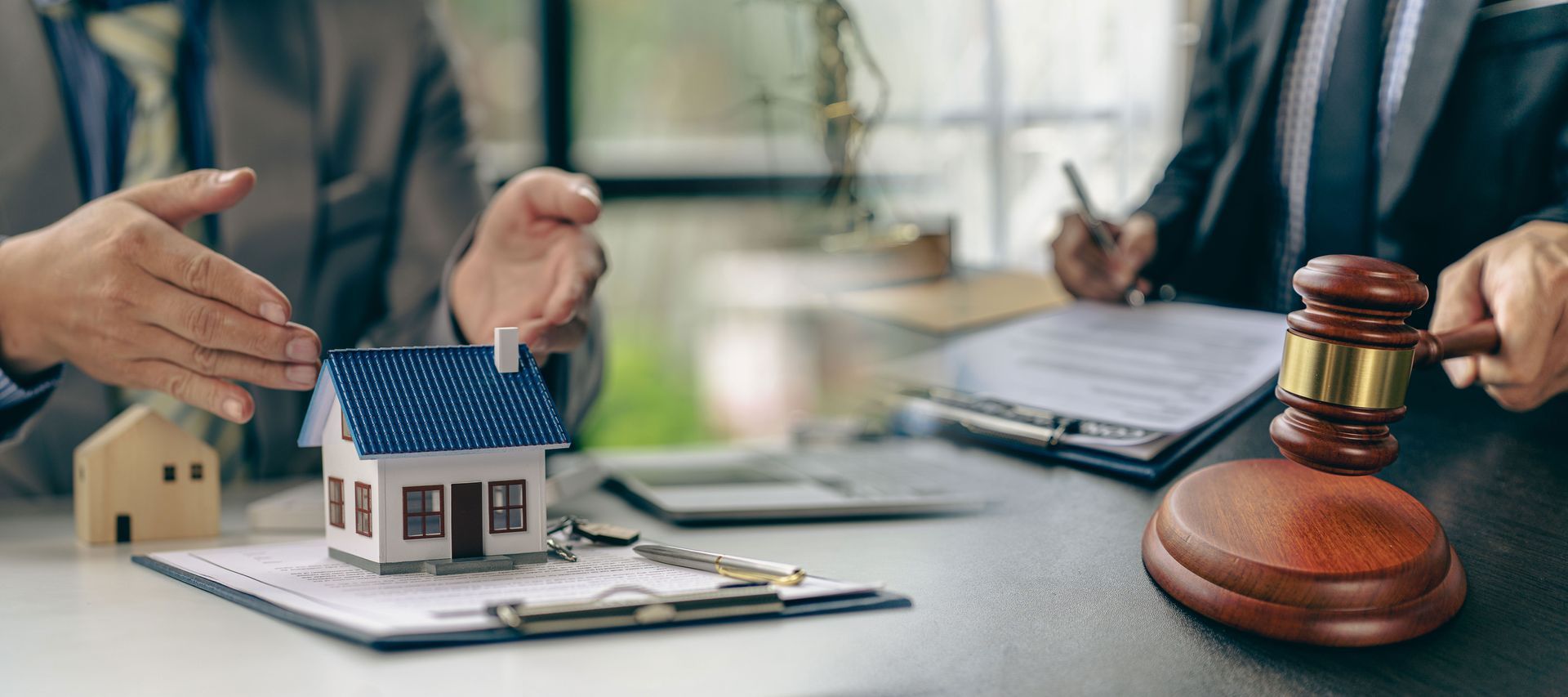 Real estate meeting with house model, documents, and gavel on desk Real estate meeting with house model, documents, and gavel on desk