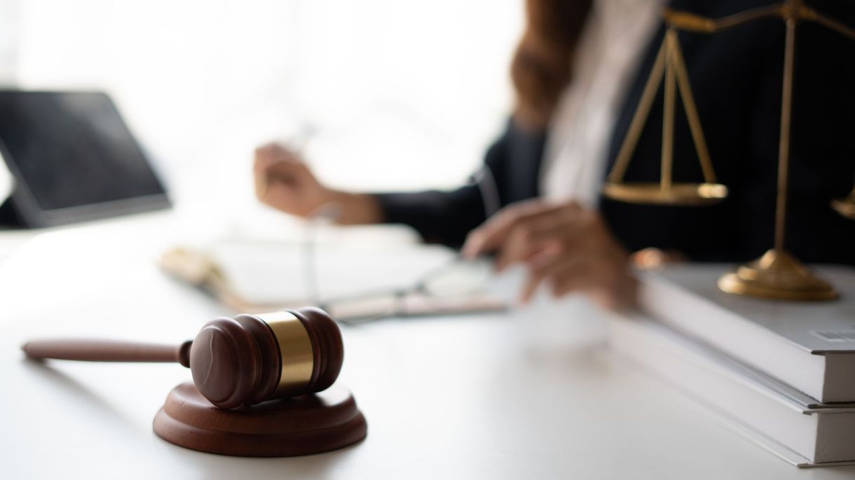 Lawyer’s desk with gavel, scales of justice, and stacked books in a bright office Lawyer’s desk with gavel, scales of justice, and stacked books in a bright office