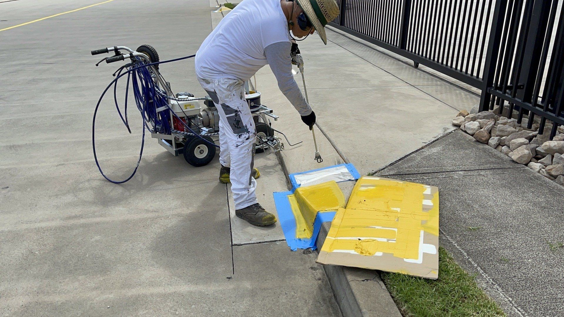 a man is painting a yellow and blue sign on the sidewalk .