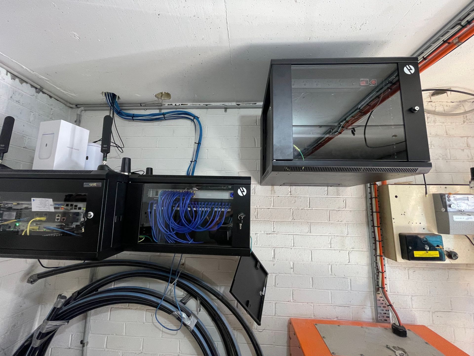 a room with a lot of wires hanging from the ceiling and boxes on the wall .