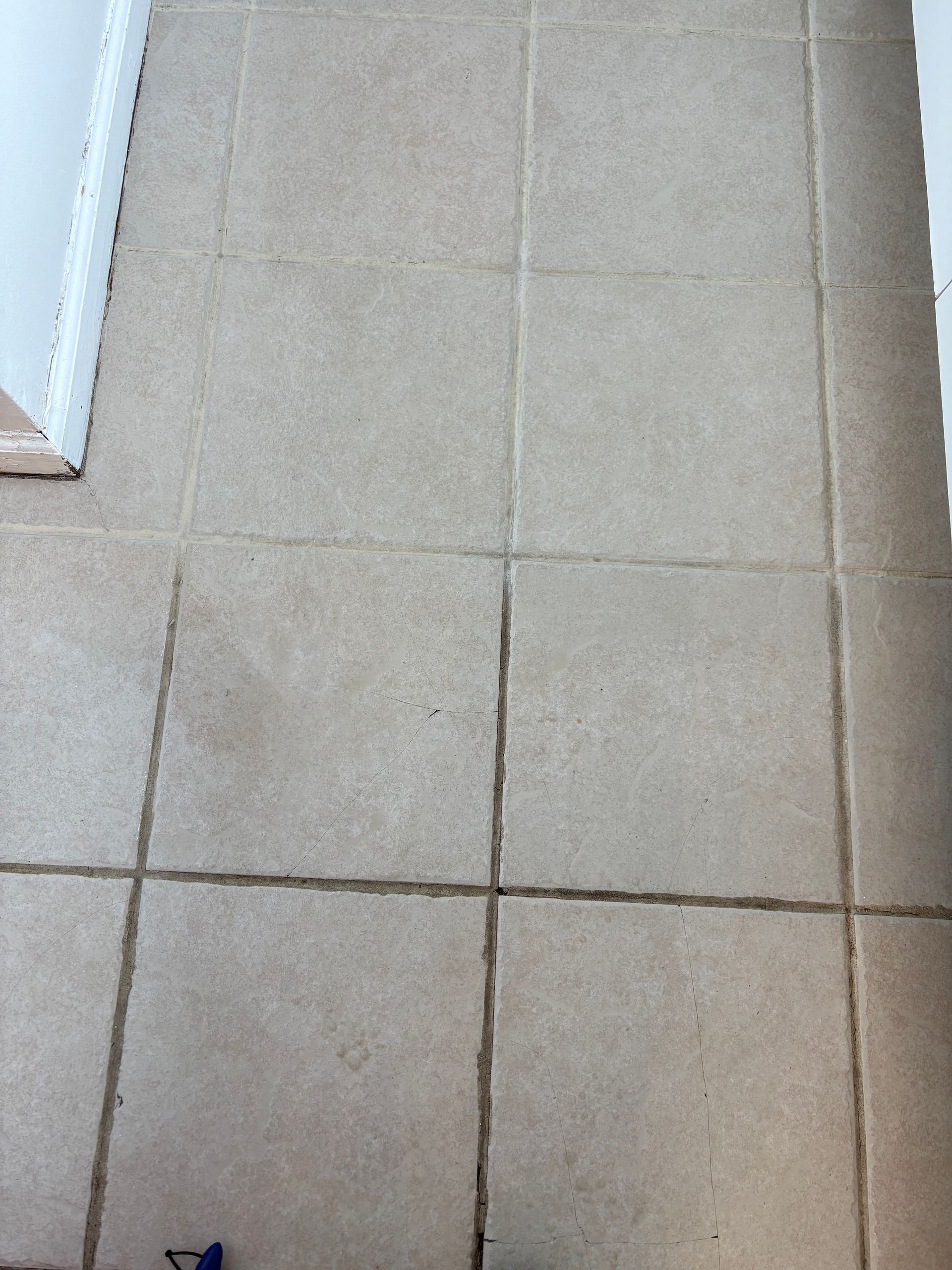 Beige tiled floor with a small dark mark near the bottom left edge