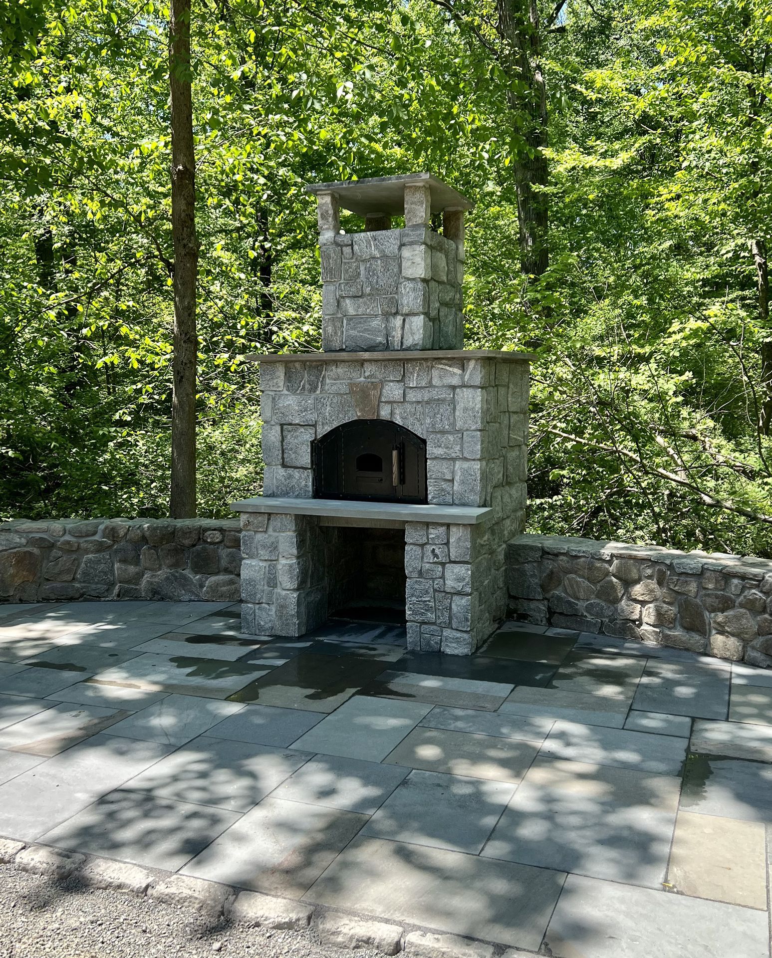 Stone outdoor fireplace with chimney in a wooded park setting