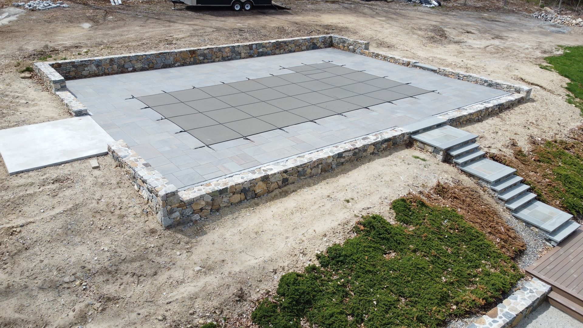 Concrete foundation slab with a stepped edge in a dirt construction site, seen from above