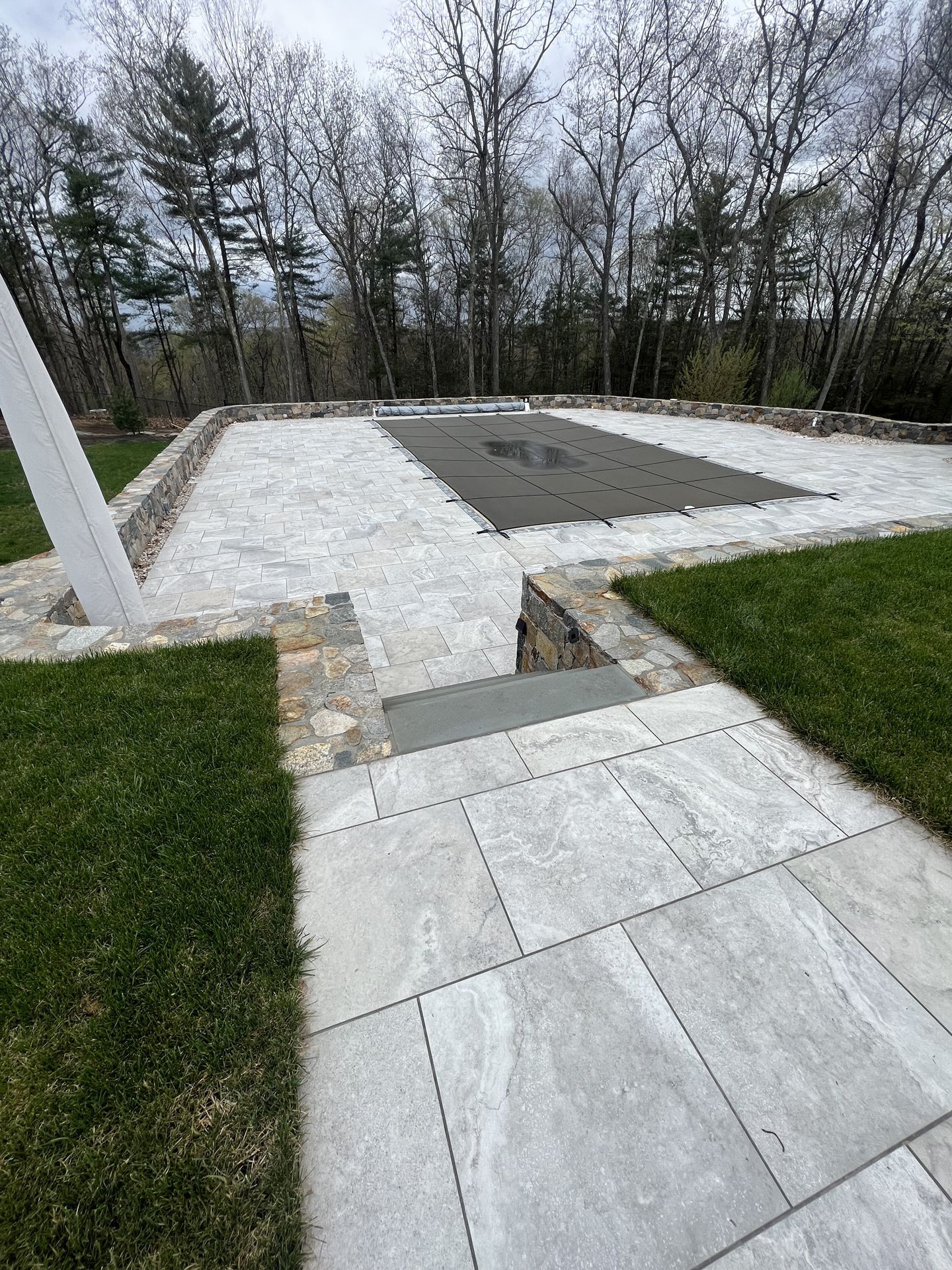 Stone patio and steps leading to a white gravel courtyard with trees in the background