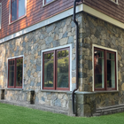 Stone-and-brick house exterior with red-trimmed windows and a grassy lawn