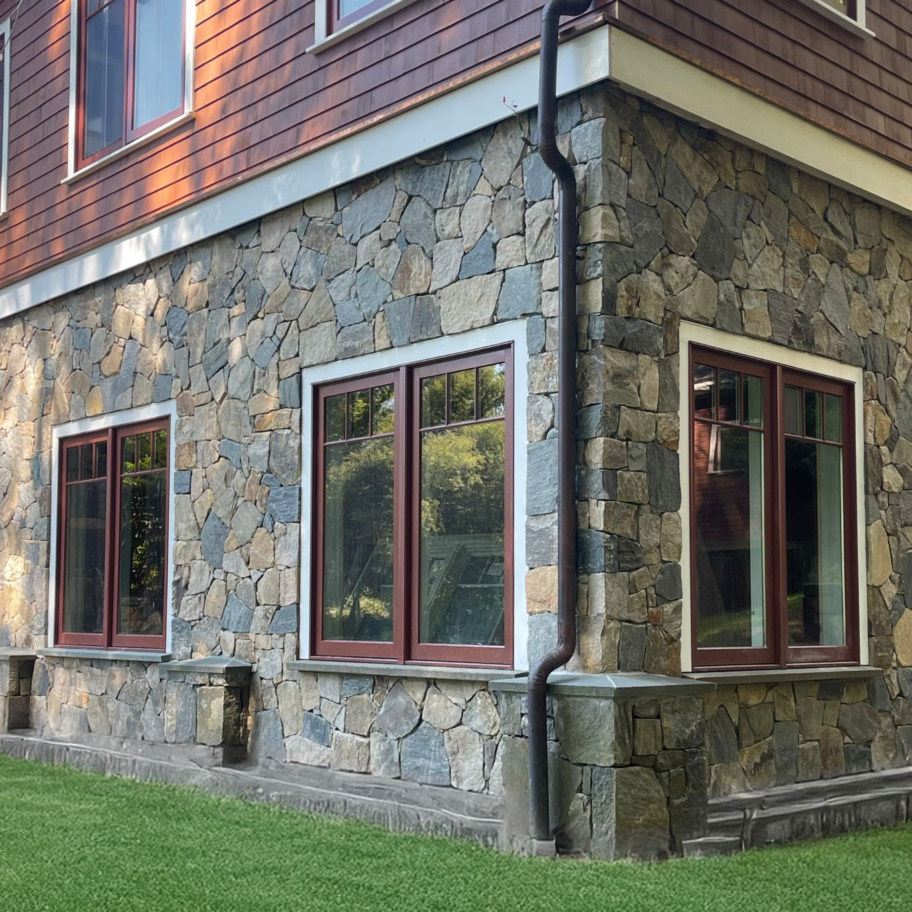 Stone-and-brick house exterior with red-trimmed windows and a grassy lawn