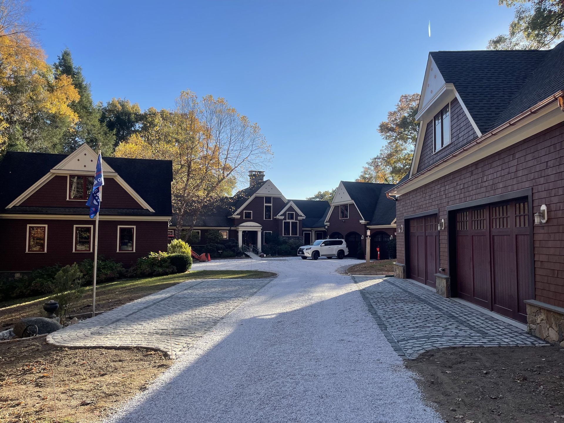 Snow-dusted gravel driveway between brick houses under a clear blue sky
