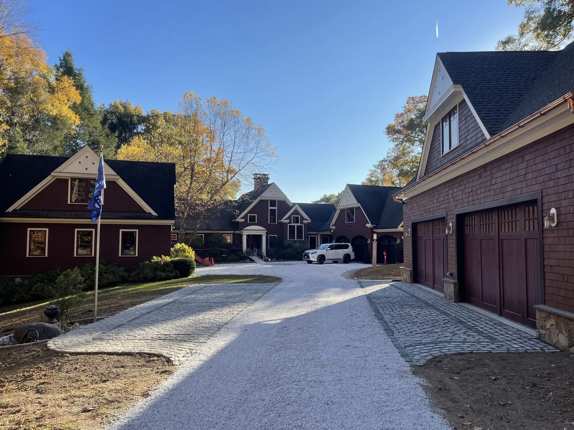 Gravel driveway between brick houses and garages on a sunny autumn day