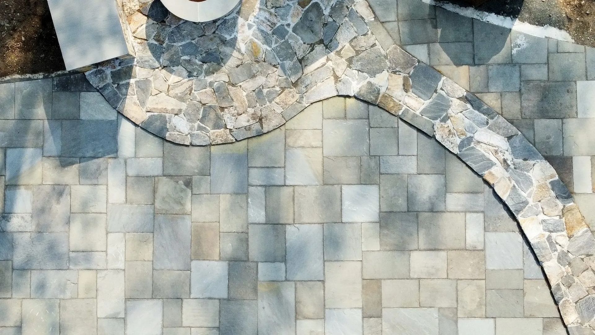 Abstract mosaic of pale gray and beige stone tiles with curved decorative bands
