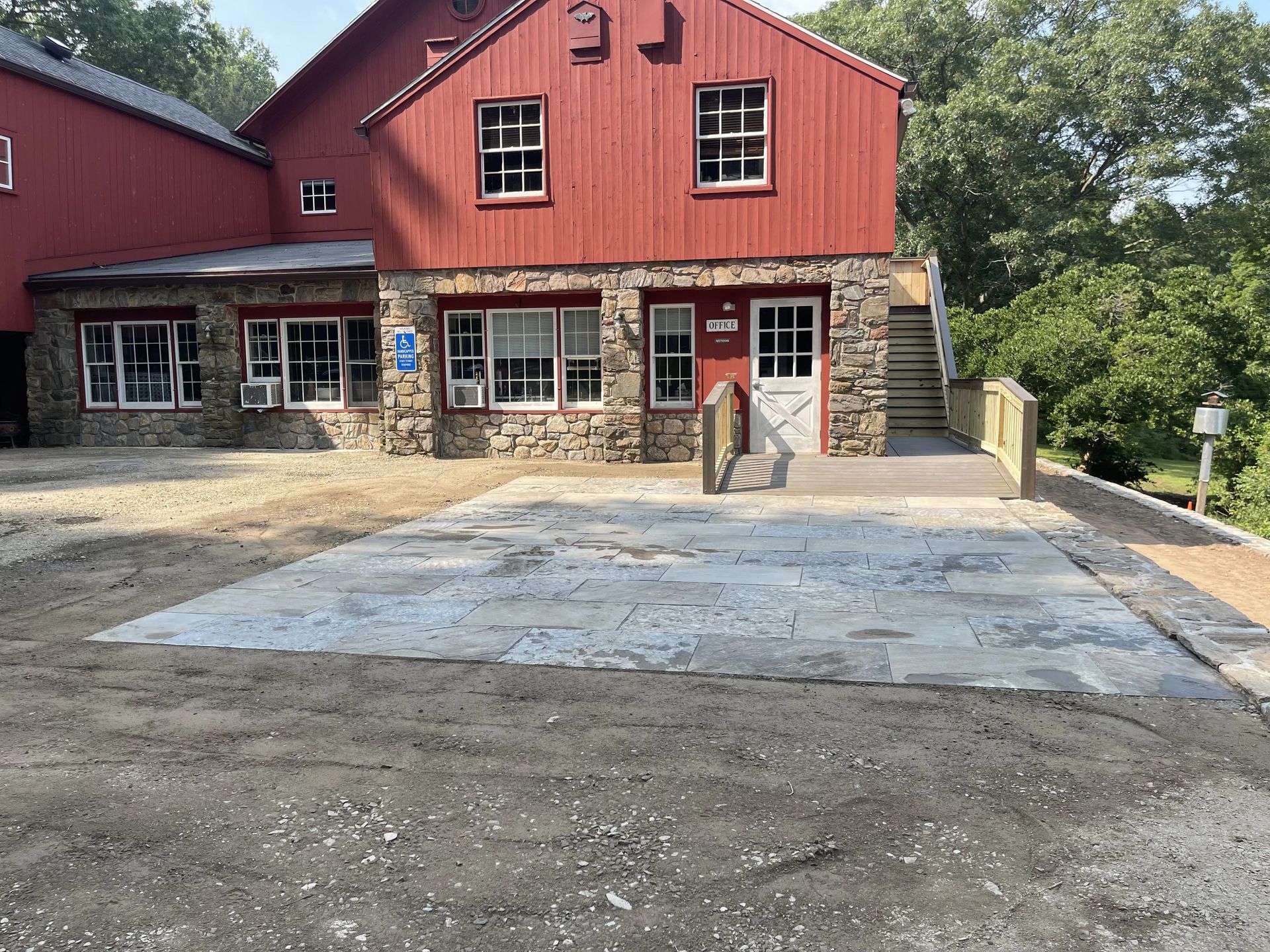 Red barn-style building with stone entry and a concrete driveway in front