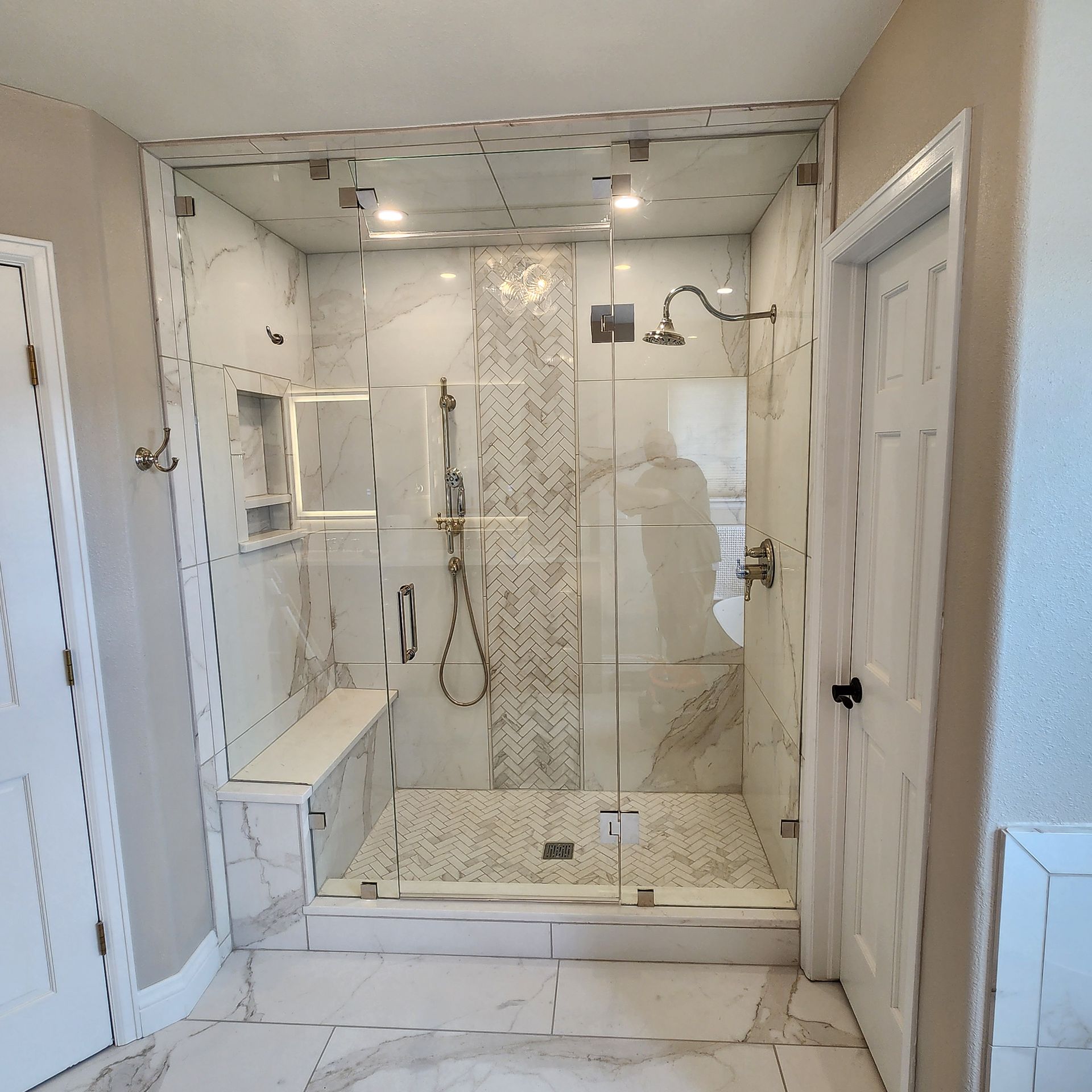 Modern white tiled walk-in shower with glass enclosure and built-in bench in a bathroom