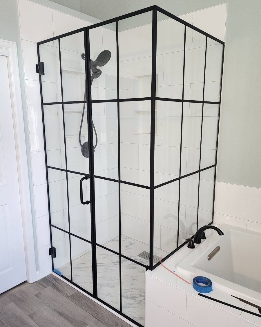 Modern tiled shower with glass doors, brass hardware, recessed shelf, and ceiling lights