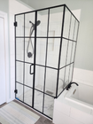 Black-framed shower enclosure with clear panels beside a bathtub in a white bathroom.