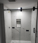 Modern bathroom shower with white marble tile, black hardware, and glass sliding door