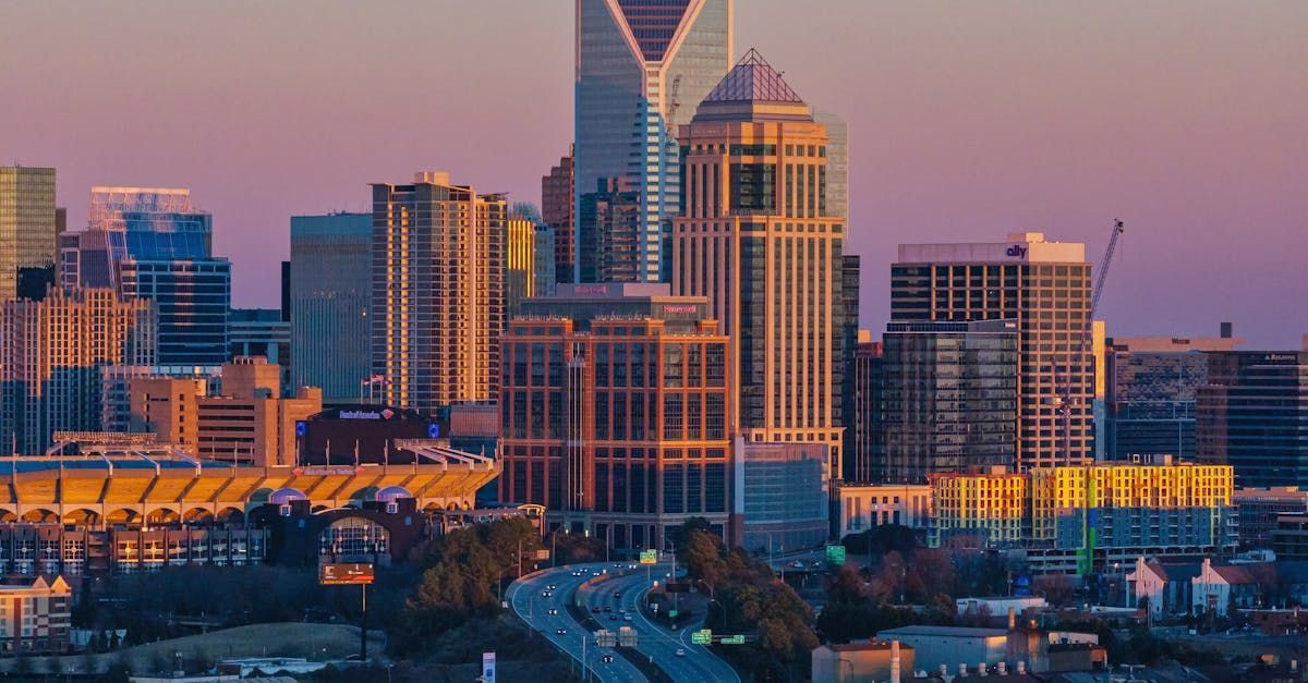 An aerial view of a city skyline at sunset with a highway in the foreground.