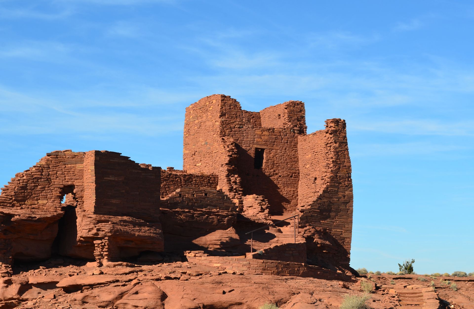 Ancient red sandstone cliff dwellings under a bright blue sky at Hovenweep National Monument.