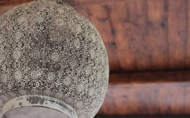 Primo piano di un oggetto in pietra o ceramica grigia screziata su uno sfondo di legno.