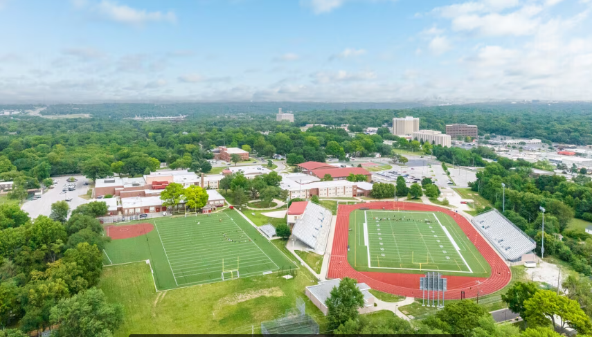 An aerial view of a school with a football field and a baseball field.