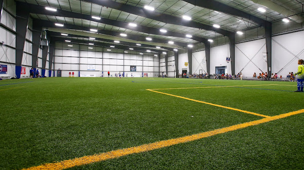 A large indoor soccer field with a yellow line in the middle.