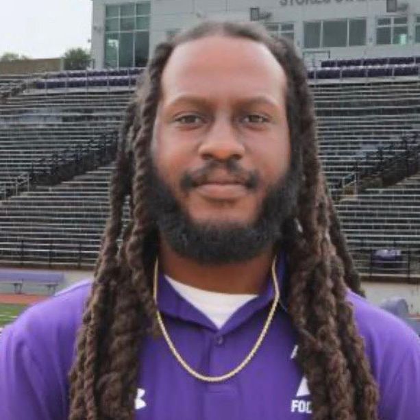 A man with dreadlocks and a beard wearing a purple shirt that says fcl