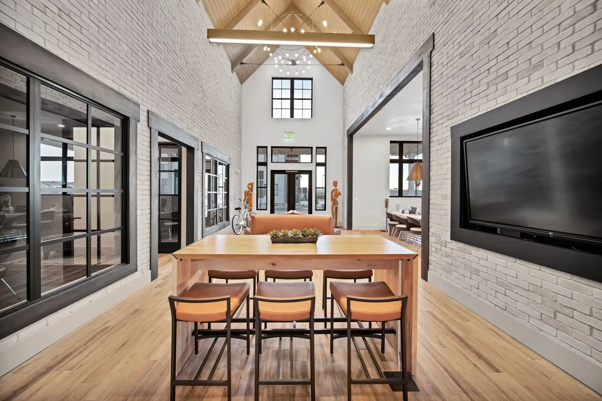 Modern loft dining area with wood table, bar stools, exposed brick, and large windows