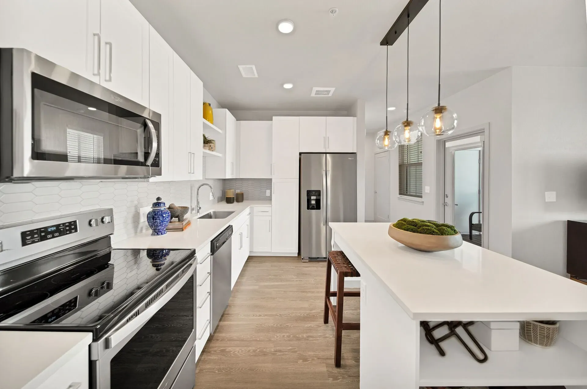 Modern kitchen with stainless steel appliances, white cabinets, and a large island.