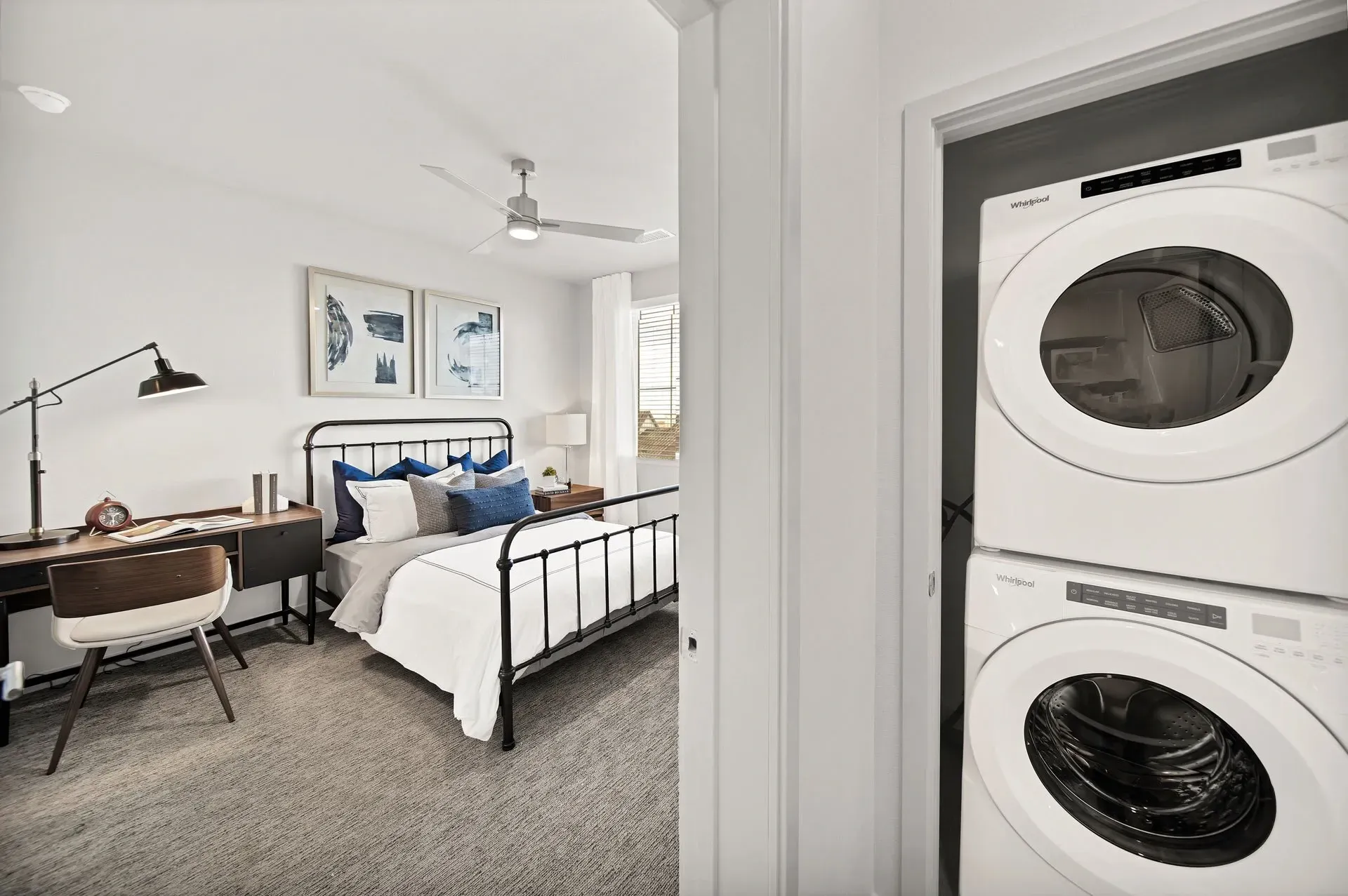 Bedroom with a desk, bed, and stacked washer/dryer in closet.