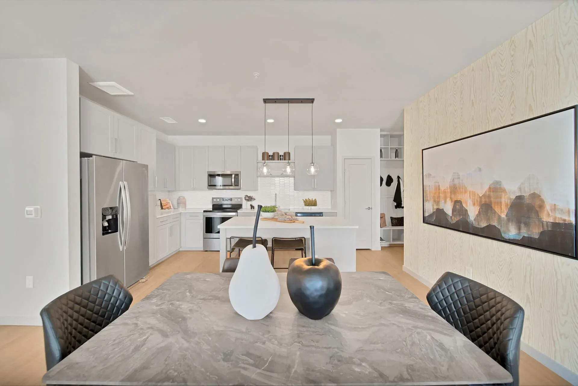 Modern open-concept kitchen and dining area with stainless steel appliances, island, and decorative elements.
