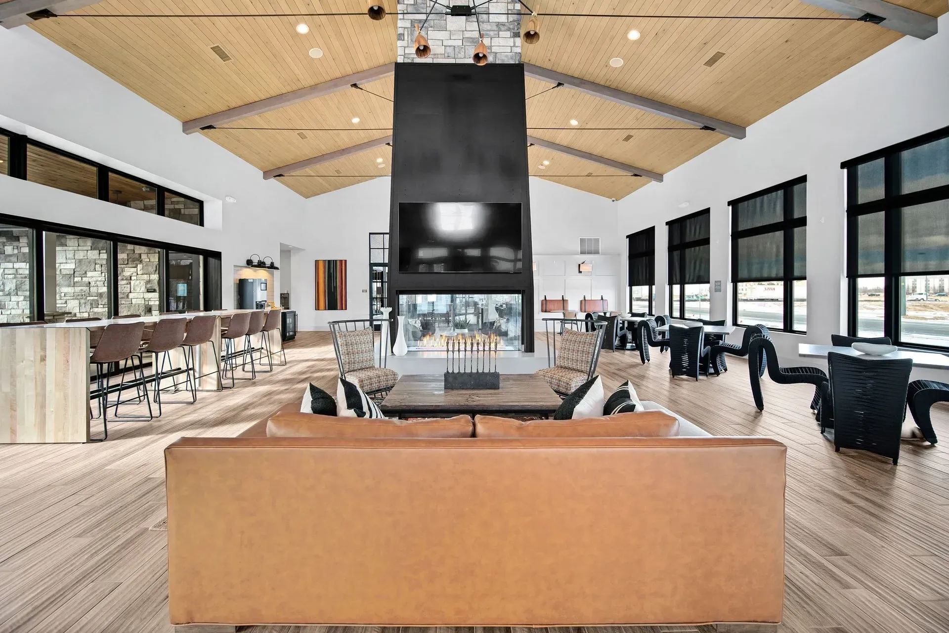 Modern lounge area with a large fireplace and TV, bar seating, and dining tables.
