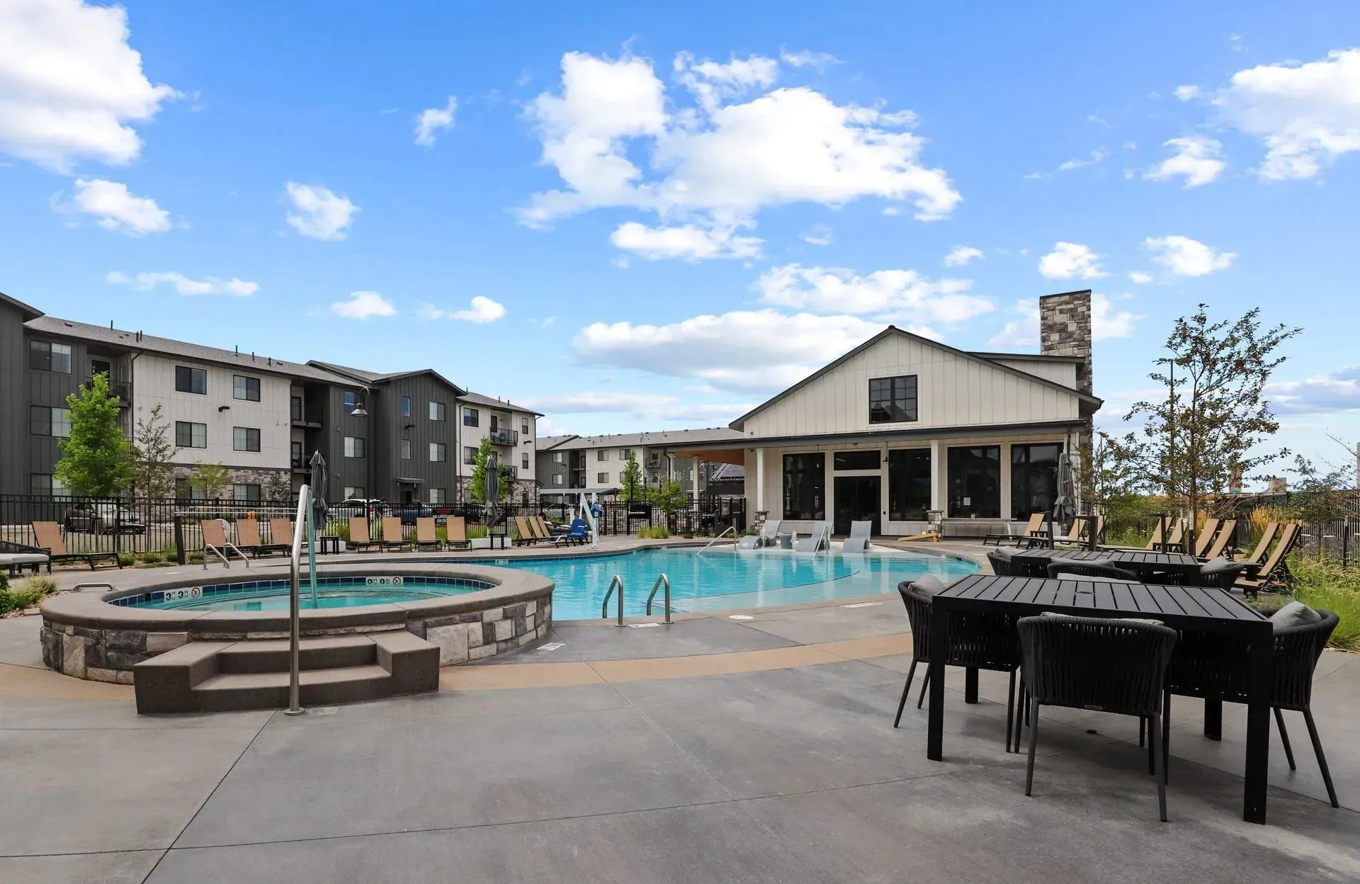 Outdoor swimming pool and hot tub area with lounge chairs and seating.